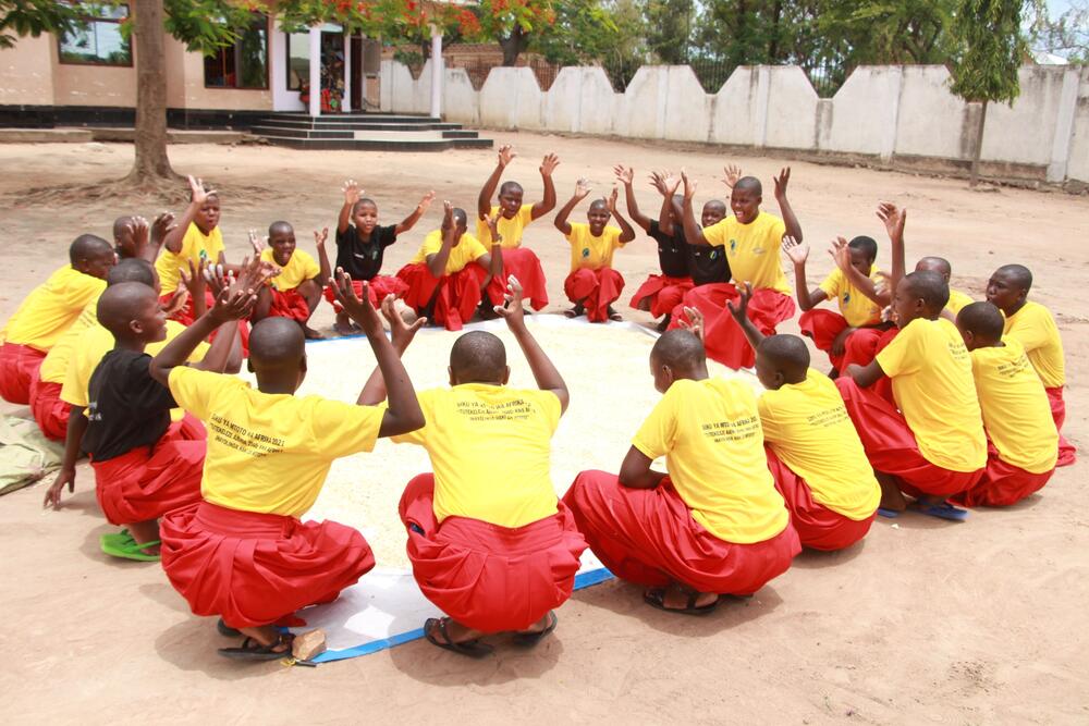 a group of kids in school clothes play in a patio.