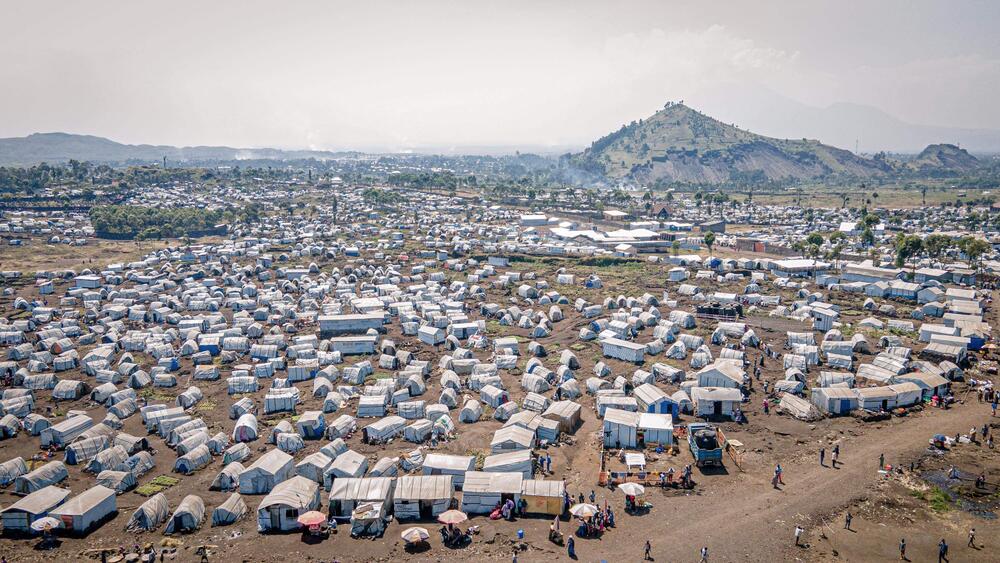 Aerial view of the Bulego IDP site. A vast array of small tents and structures is spread across orange soil with sparse trees.