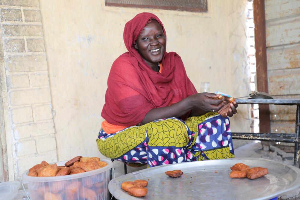 A smiling woman looks at the camera while showing the bread she made.