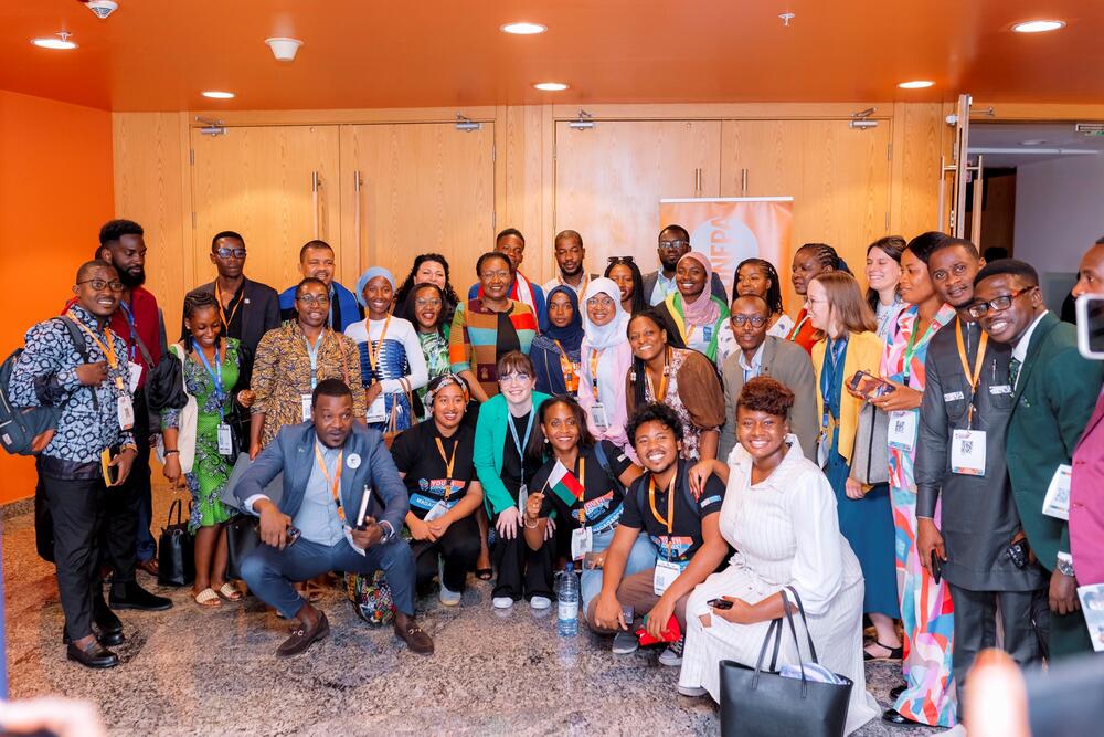 A large group of young innovators smile to the camera, all huddled up together.