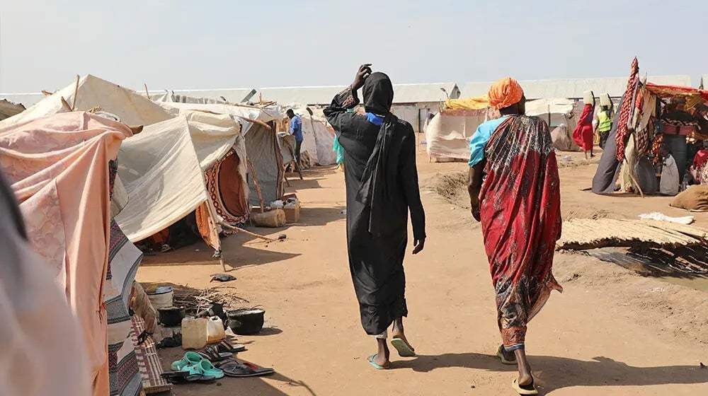 Two women walk inside a IDP site in Renk.