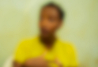 A blurred image shows a young person speaking with their lifted hands. 