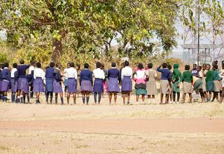 A group of young women stand in an open field talking. 