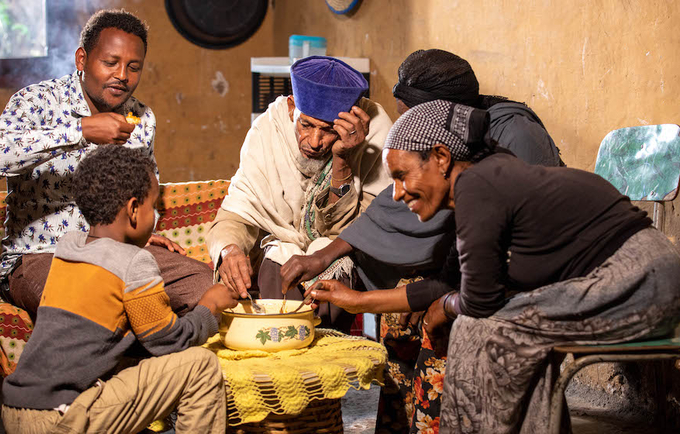 UNFPA-supported midwife Abiyot, who facilitated Setyelem's safe delivery, eats traditional porridge with his family in Kara Kore
