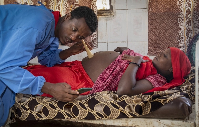 Kemal Hassan, a midwife mentor in Ethiopia, examines a patient while using an app.