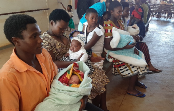 A man waiting in a queue to immunize their baby at Bududa Hospital 