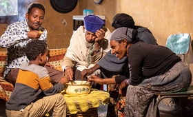 UNFPA-supported midwife Abiyot, who facilitated Setyelem's safe delivery, eats traditional porridge with his family in Kara Kore