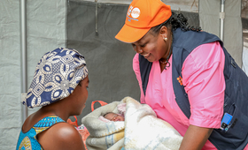 Midwife Fyfy Omoyi hands Ms. Bembeleza her newborn, who was delivered safely at the UNFPA mobile health clinic.