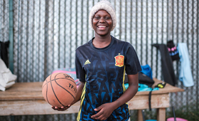 A young woman with a basketball ball in Kibera, Nairobi, Kenya.