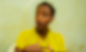 A blurred image shows a young person speaking with their lifted hands. 