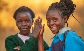 Two young women high five while smiling. 