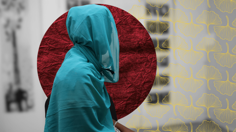 Veiled woman sits on a brightly lit room. The silhouette of her face is barely visible through her veil. 