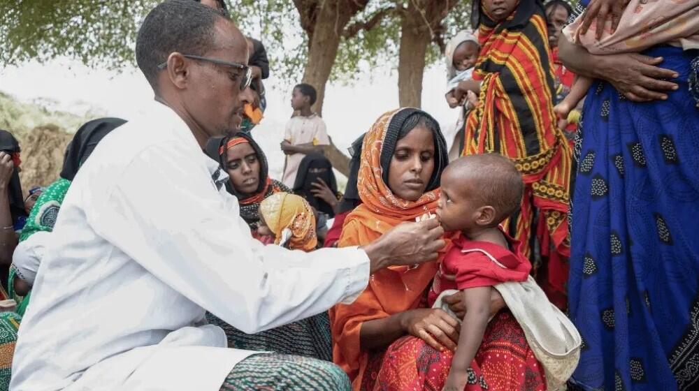 Osman providing a nutritional supplement to Fatuma's child.