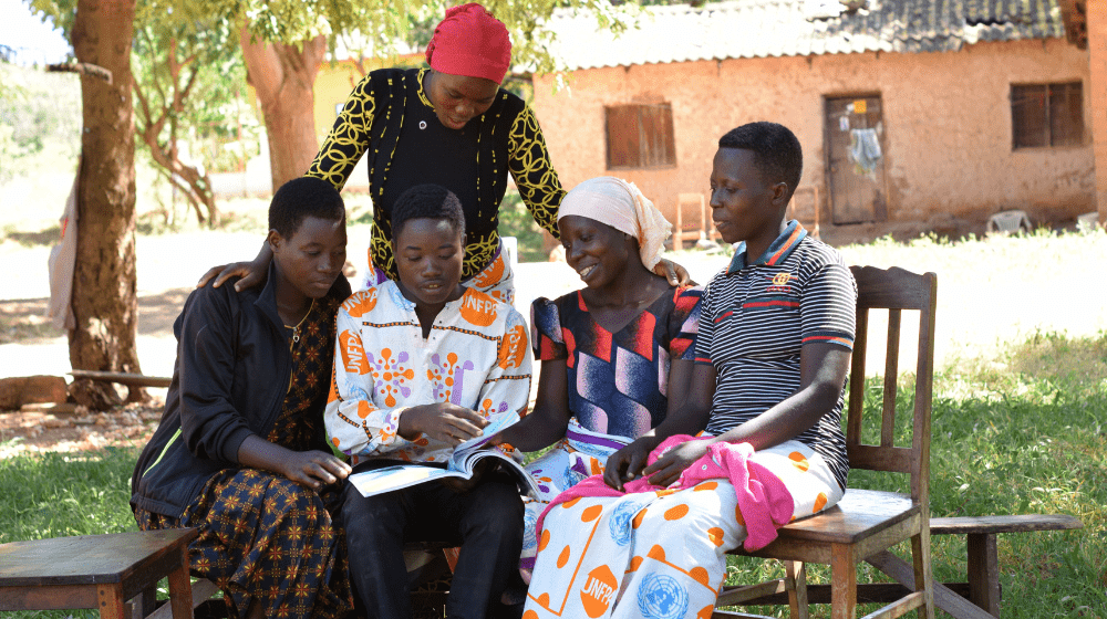 Melania Zambiliti (standing) alongside members of the Upendo group, who have gained entrepreneurial skills that provide them with an income, while also learning about sexual and reproductive health. Together, they have built a strong sense of unity and shared purpose. 