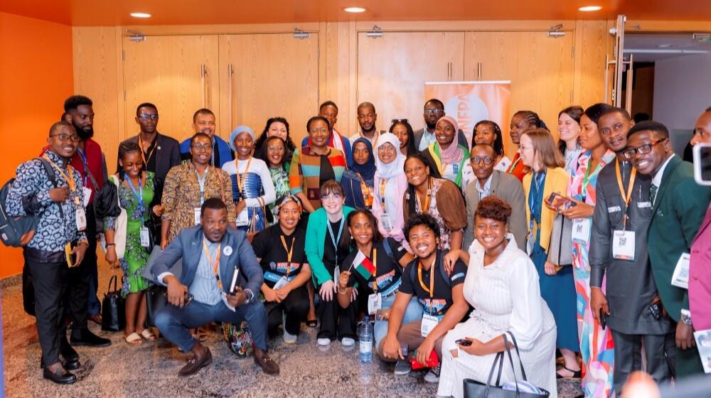 A group of young participants of the hacklab are huddled together smiling together with UNFPA Staff and Regional Director Lydia Zigomo.