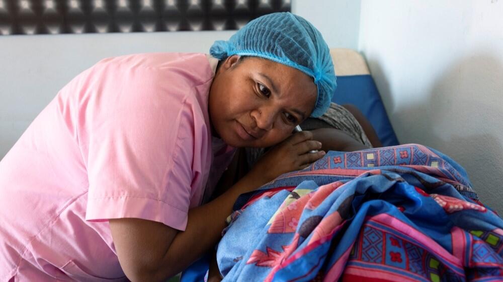 Nurse Sitraka examines a pregnant woman's abdomen and listens to a pregnant woman's abdomen through a pinard stethoscope.