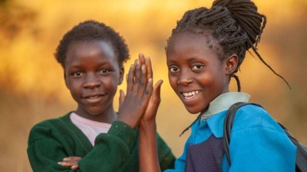 Two young women high five while smiling. 